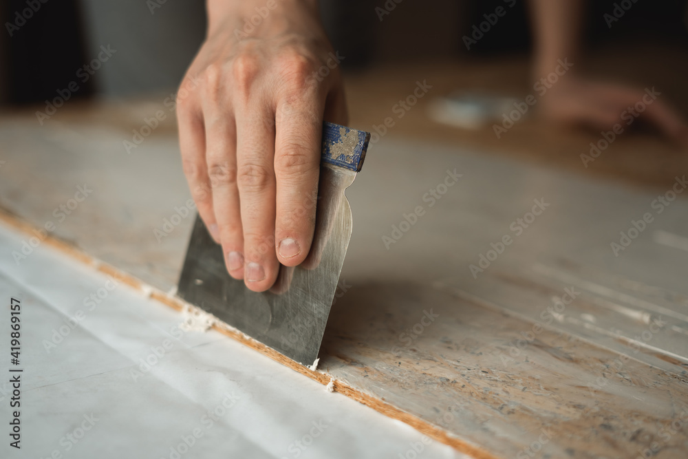 Hand applies the putty with a spatula Hand applies the putty with a spatula