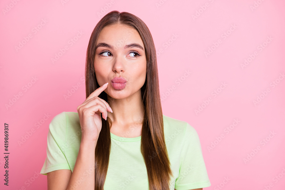 Photo of flirty tricky young lady wear green t-shirt finger pouted lips looking empty space isolated pastel pink color background Photo of flirty tricky young lady wear green t-shirt finger pouted lips looking empty space isolated pastel pink color background