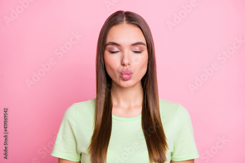 Photo of adorable dreamy young girl dressed green t-shirt lips plump closed eyes isolated pastel pink color background