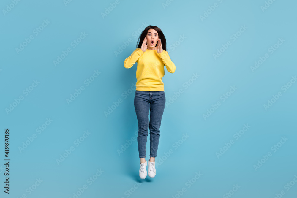 Photo of shocked announcer lady jump palms open mouth scream wear yellow jumper jeans shoes isolated blue background Photo of shocked announcer lady jump palms open mouth scream wear yellow jumper jeans shoes isolated blue background
