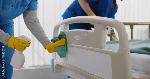 Team of professional janitors using equipment disinfecting hospital ward photo