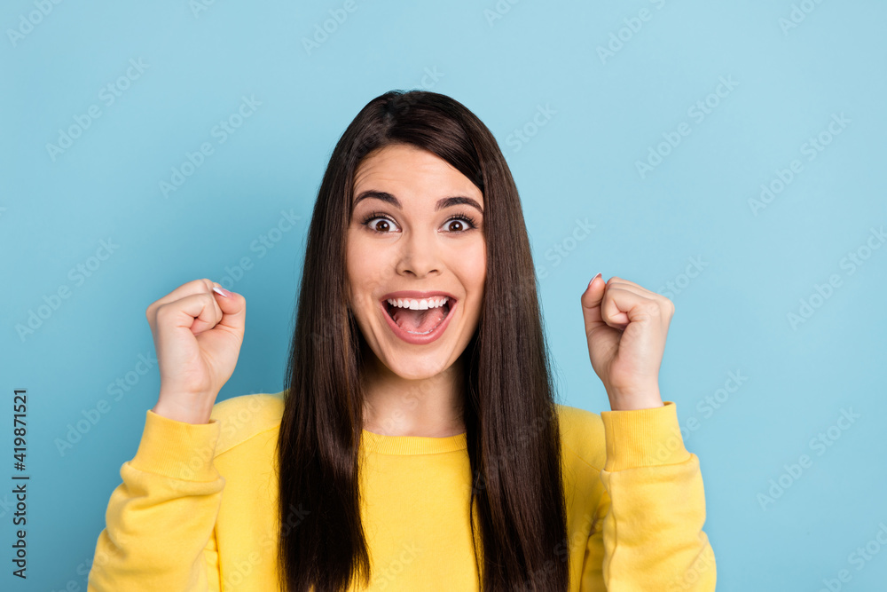 Photo of cheerful astonished lady open mouth scream raise fists wear yellow jumper isolated blue background Photo of cheerful astonished lady open mouth scream raise fists wear yellow jumper isolated blue background