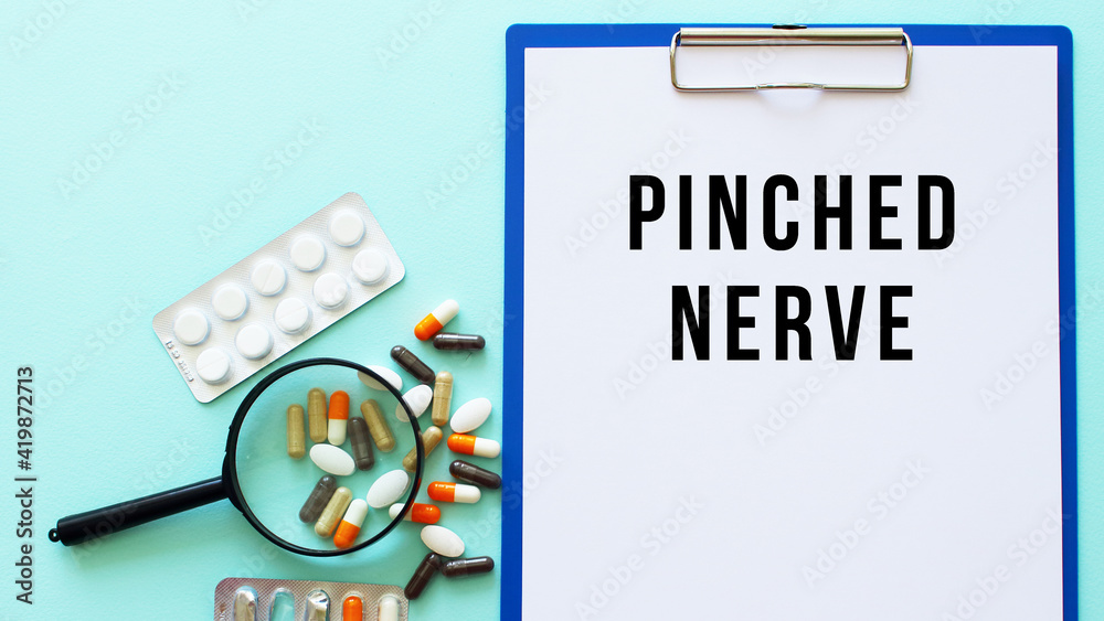 A clipboard with paper lies on a table near drugs. Inscription PINCHED NERVE. A clipboard with paper lies on a table near drugs. Inscription PINCHED NERVE.