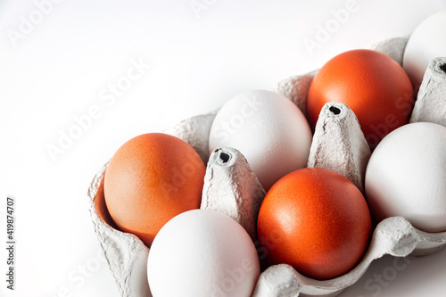 White and brown chicken eggs in a carton on a light background.