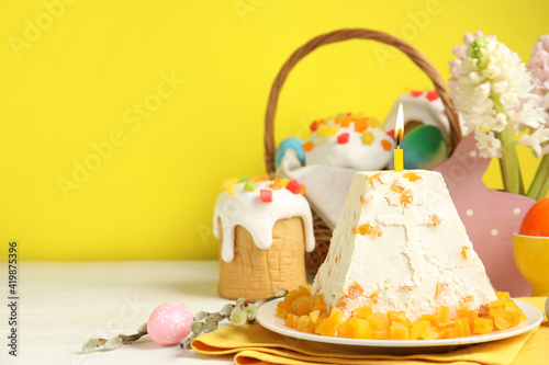 Traditional cottage cheese Easter paskha with dried apricot and burning candle on white wooden table, space for text