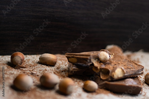 chocolate sprinkled with cocoa on sacking, dark background behind and space for text. Chocolate with hazelnuts