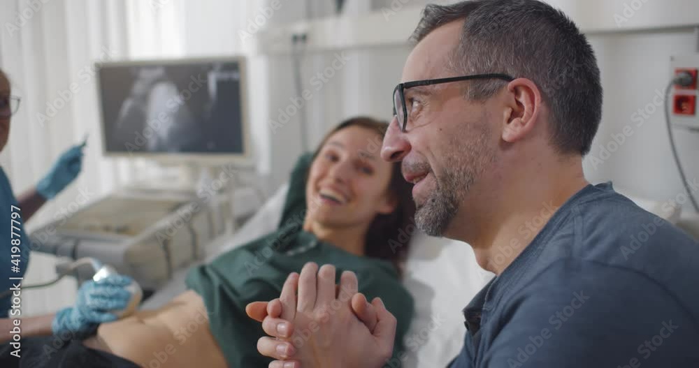 Gynecologist performing ultrasound scanning for pregnant couple Gynecologist performing ultrasound scanning for pregnant couple
