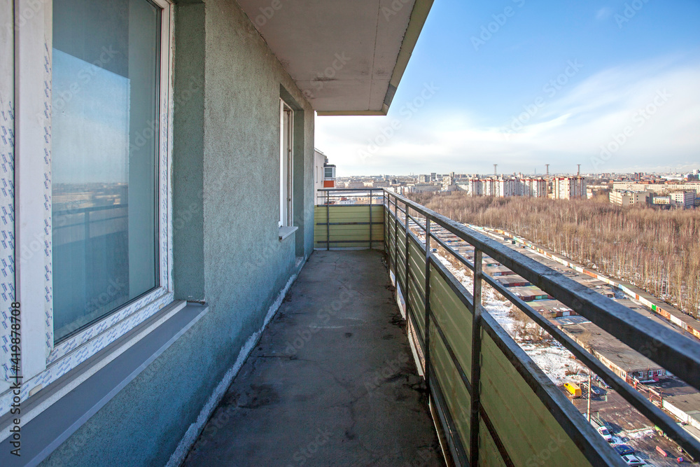 Open long balcony in a Russian apartment with a view of the winter city .