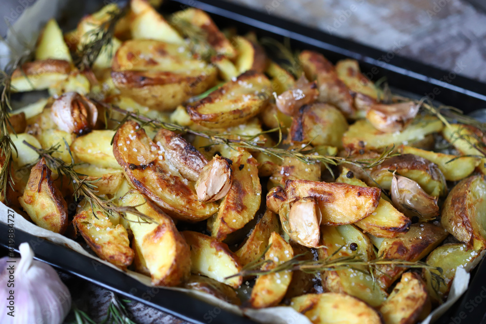 Appetizing baked potato wedges. Country-style potatoes on a baking sheet. Potatoes with herbs and garlic. Appetizing baked potato wedges. Country-style potatoes on a baking sheet. Potatoes with herbs and garlic.
