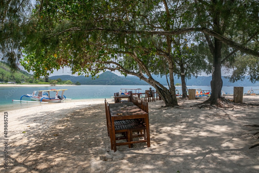 The beach with a traditional boat and tables in Lombok Island of East Indonesia. The beach with a traditional boat and tables in Lombok Island of East Indonesia.