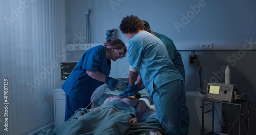 Medical team making cardiopulmonary resuscitation to male patient in hospital photo
