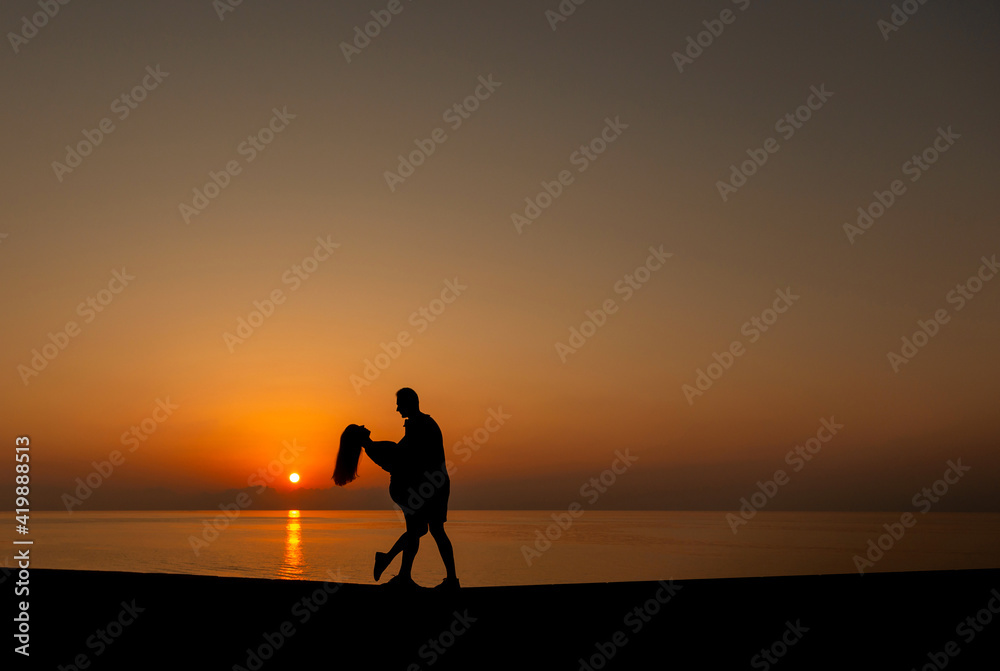 Silhouette of two young people on the beach in sunset