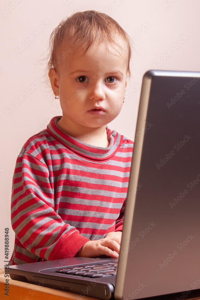 Young programmer. Humorous photo of a little baby girl working with a laptop. Young programmer. Humorous photo of a little baby girl working with a laptop.