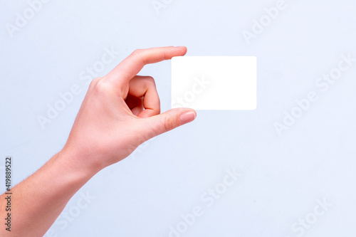 female hand holding white card mockup on gray background