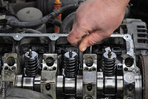 Car mechanic fixing modern diesel engine, closeup of hand with socket bit removing injectors from cylinder head