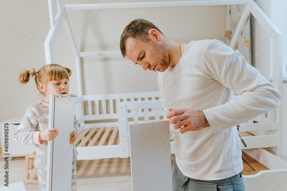 Fototapeta premium Father with daughter fixing the drawer of kids bed