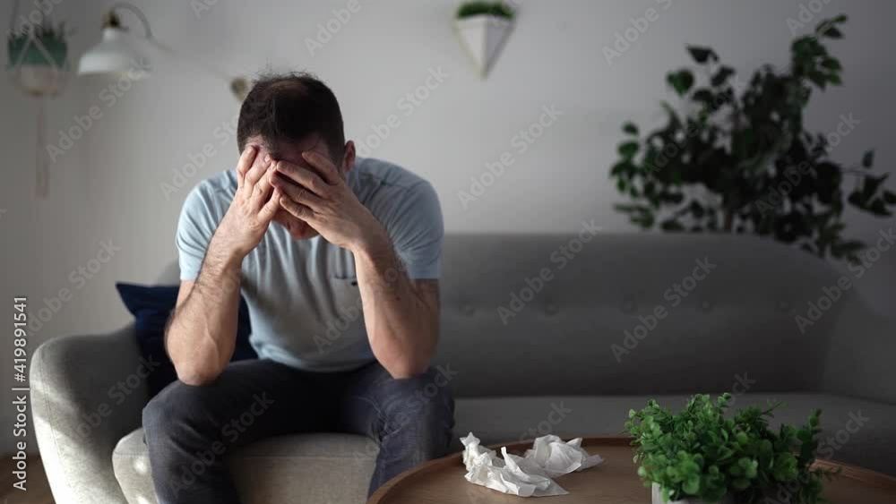 A Frustrated handsome man with problem sitting on the couch at home with tissue on the front