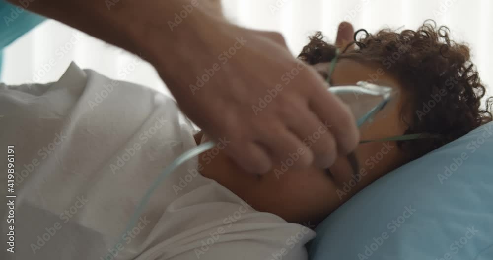 Nurse adjusting oxygen mask on woman patient lying in bed