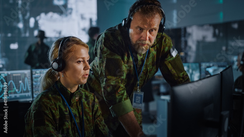 Military Surveillance Officers Talking Next to a Computer Screen in Central Office for Cyber Operations, Control and Monitoring for Managing National Security, Technology and Army Communications.