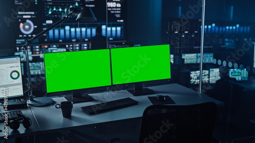 Two Digital Computer Screens with a Green Mock Up Chromakey in Modern Monitoring Office. Control Room with Specialists and Managers Sit in Front of Computers. 