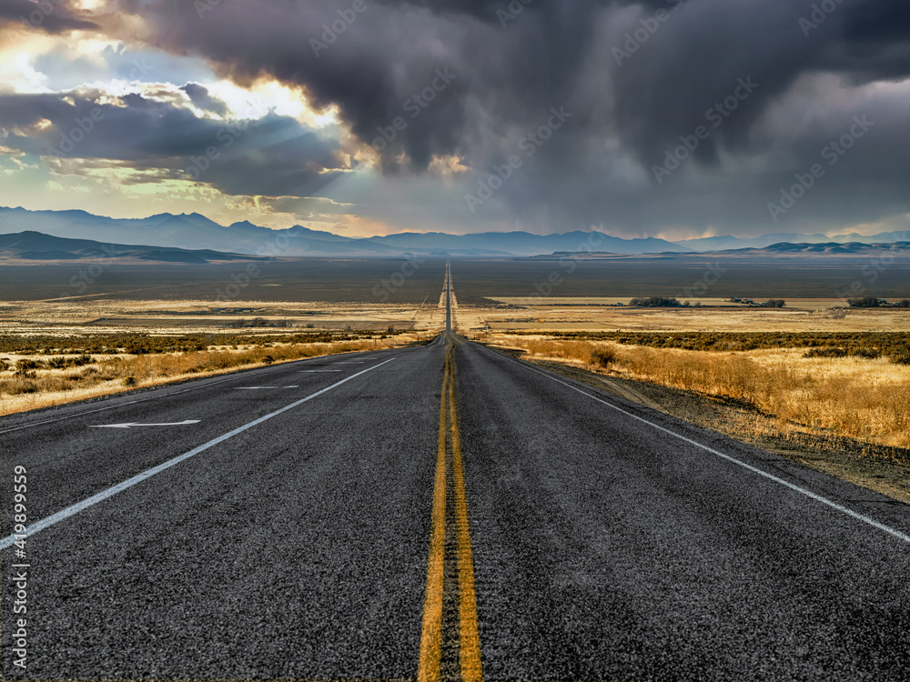 Straight road leading through storm clouds in the stormy Nevada desert landscape