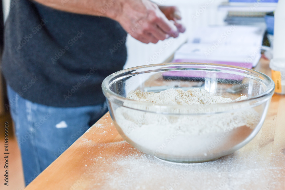 Person making bread in home kitchen adding ingredients to make the dough Person making bread in home kitchen adding ingredients to make the dough