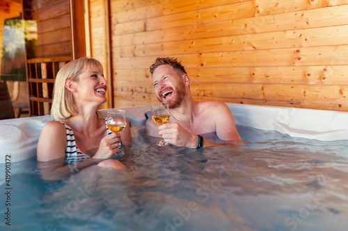Obraz na płótnie Couple relaxing and drinking wine in a hot tub