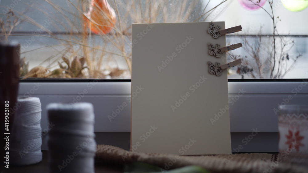 Kartka papieru pastelowa na parapecie przy oknie w dzień - obrazy, fototapety, plakaty 