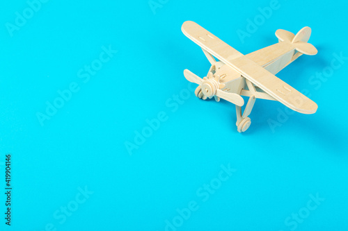Fototapeta Naklejka Na Ścianę i Meble -  Model of a wooden toy plane, airliner, on a blue background. the concept of travel and transport and children's fantasies