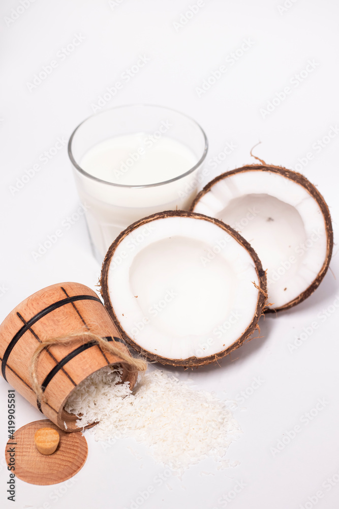 opened coconut near coconut flakes in wooden bowl and glass of coconut milk isolated on white background. tropical, nut. coco. opened coconut near coconut flakes in wooden bowl and glass of coconut milk isolated on white background. tropical, nut. coco.