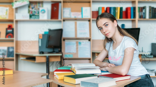 Back to school, reading book, education, library concept. Student girl with book on background of bookshelves in the library.