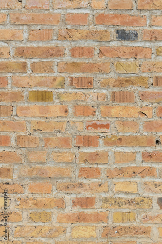 Symmetrical brick wall background. Red and brown colored terracotta bricks from an abandoned house, some clean, some dirty. Cracks in the wall.