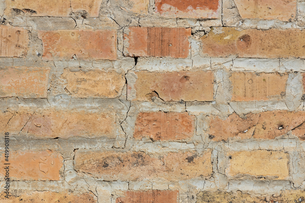 Symmetrical brick wall background. Red and brown colored terracotta bricks from an abandoned house, some clean, some dirty. Cracks in the wall. Symmetrical brick wall background. Red and brown colored terracotta bricks from an abandoned house, some clean, some dirty. Cracks in the wall.
