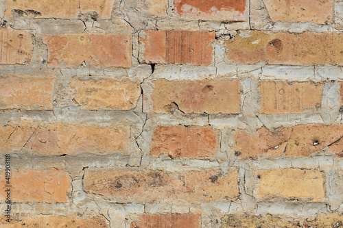 Symmetrical brick wall background. Red and brown colored terracotta bricks from an abandoned house, some clean, some dirty. Cracks in the wall.