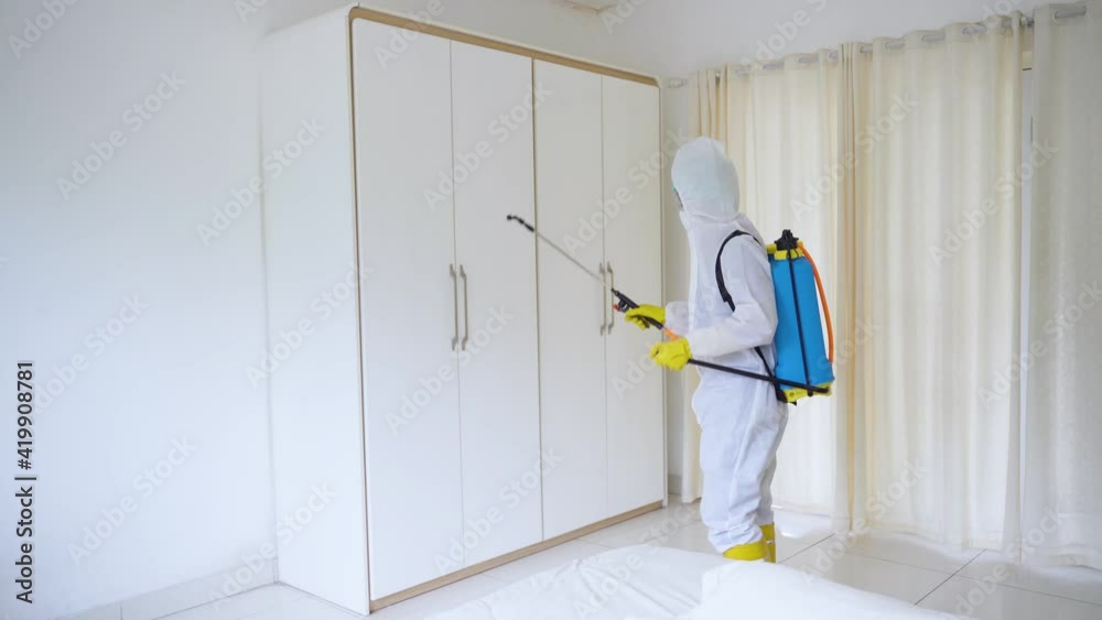 Worker cleaning wardrobe with disinfectant spray