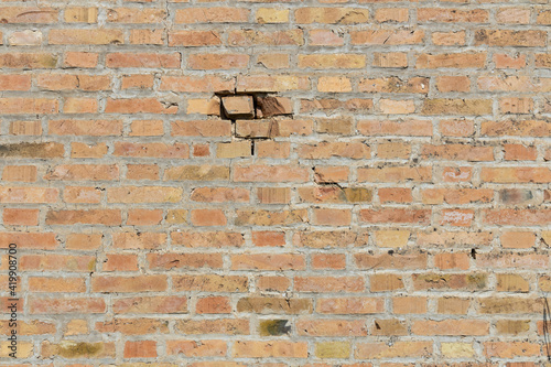 Symmetrical brick wall background. Red and brown colored terracotta bricks from an abandoned house, some clean, some dirty. Cracks in the wall.