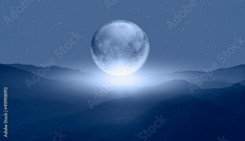 Full glass moon (or crystal ball moon) rising over blue mountain 