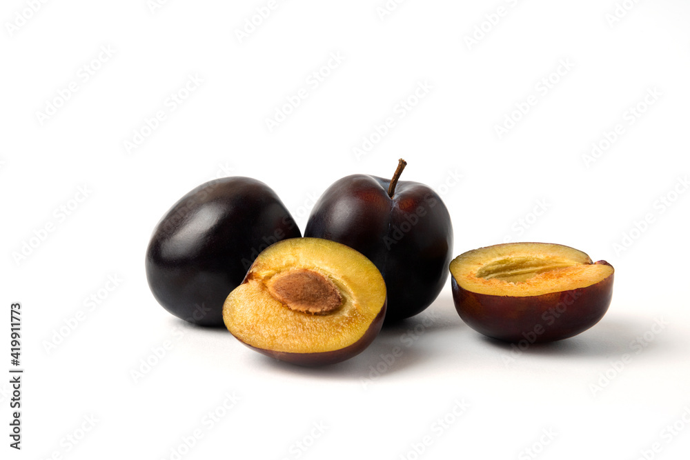 Fototapeta premium Whole and sliced black cherry plums on the white table