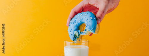 Foto Man hand holding a vibrant and delicious bitten blue doughnut with condensed milk
