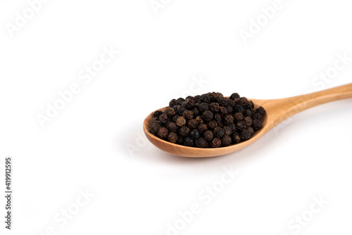 Spoon of pepper grains on white background