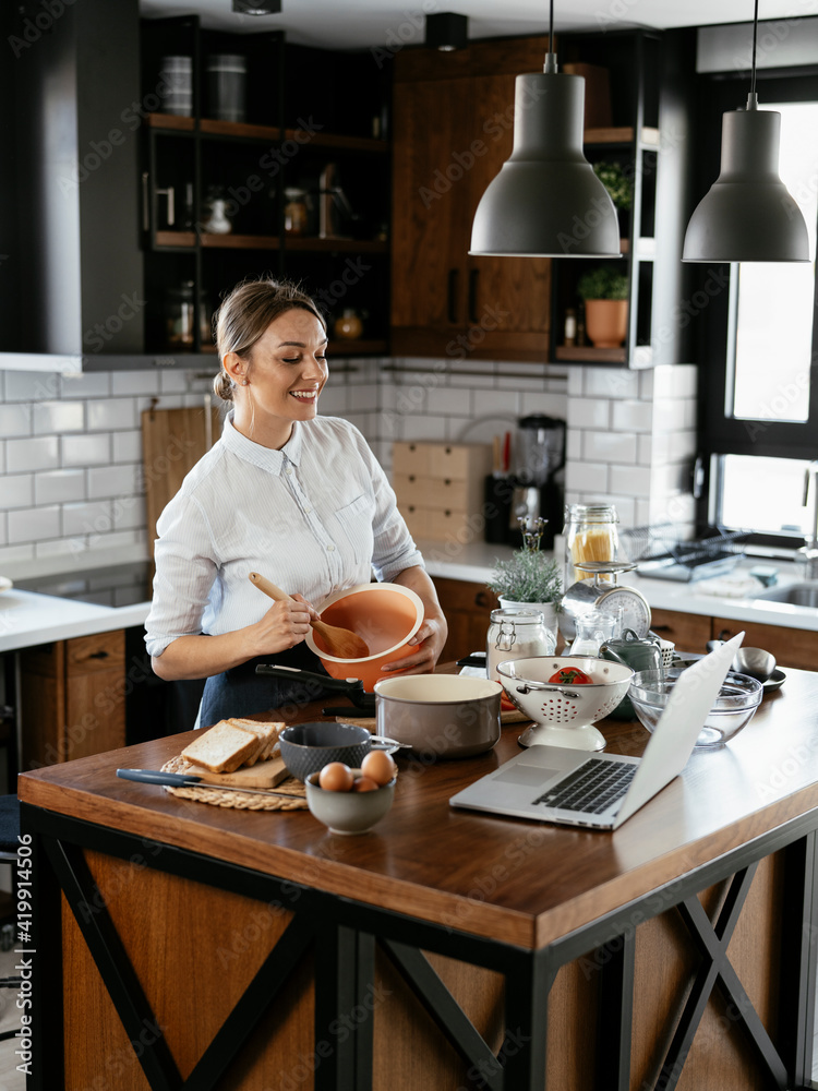 Young woman in kitchen. Beautiful woman following recipe and cooking.. Young woman in kitchen. Beautiful woman following recipe and cooking..