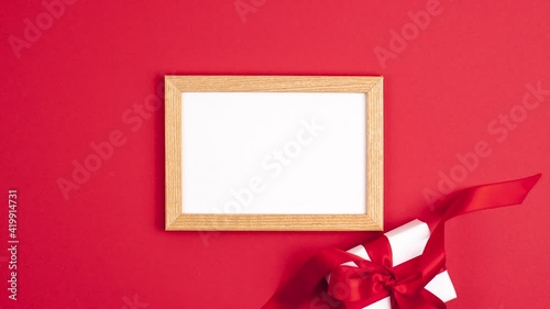 Stop motion animation mockup wooden frame flat lay of white gift box with a red satin ribbon bow on the left on vibrant red background. Mothers day holiday presents happy birthday concept copy space
