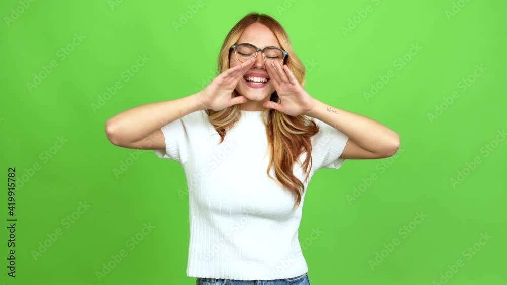 Young blonde girl with glasses shouting and announcing something over isolated background on green screen chroma key Young blonde girl with glasses shouting and announcing something over isolated background on green screen chroma key