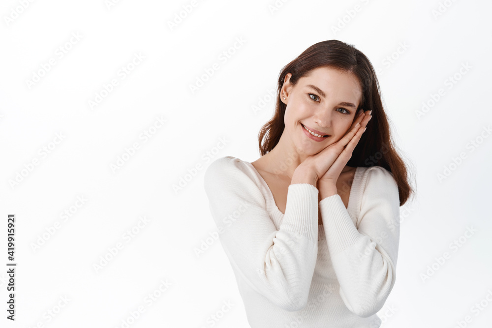 So cute. Beautiful and gently girl leans her face o hands and smiling, gazing at something with admiration and delight, enjoy view, standing against white background So cute. Beautiful and gently girl leans her face o hands and smiling, gazing at something with admiration and delight, enjoy view, standing against white background