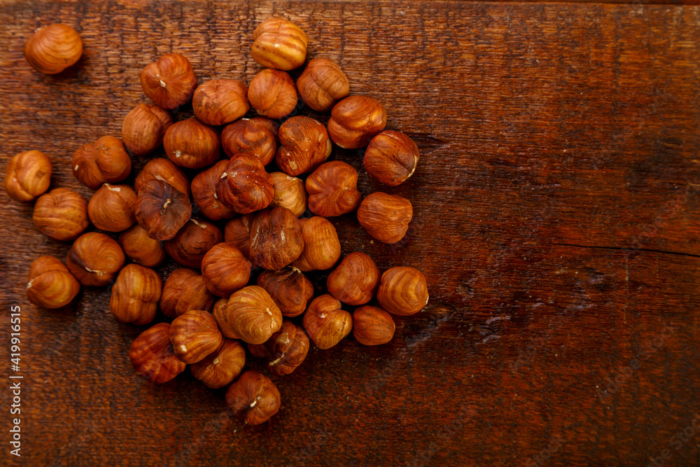 Roasted hazelnuts scattered on a wooden table. Roasted hazelnuts scattered on a wooden table.
