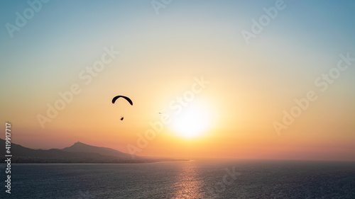Parachuting - Paragliding in sunset © kanellos