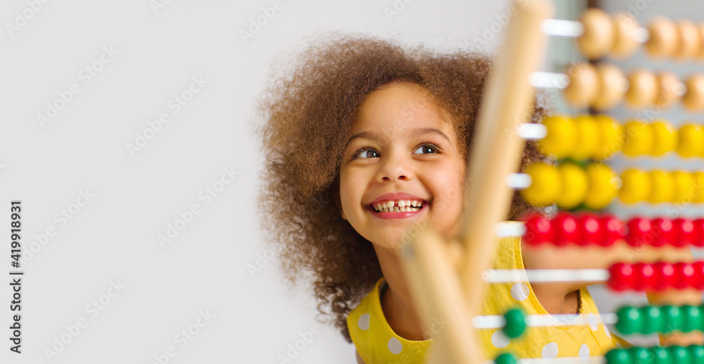 banner of A Black student in a yellow dress laughs brightly behind a colored abacus in an elementary school - obrazy, fototapety, plakaty 