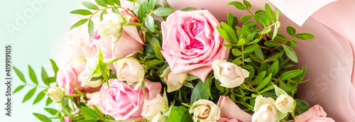 Mothers day  womens day or birthday greetings concept. Beautiful bouquet of blooming delicate pink roses and spring greenery on a green background. Banner.