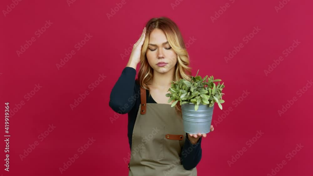 Young blonde girl holding a plant unhappy and frustrated with something over isolated background Young blonde girl holding a plant unhappy and frustrated with something over isolated background