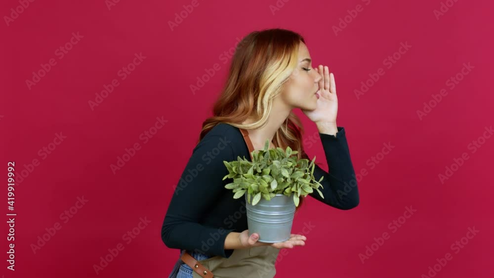 Young blonde girl holding a plant shouting to the lateral and announcing something over isolated background Young blonde girl holding a plant shouting to the lateral and announcing something over isolated background